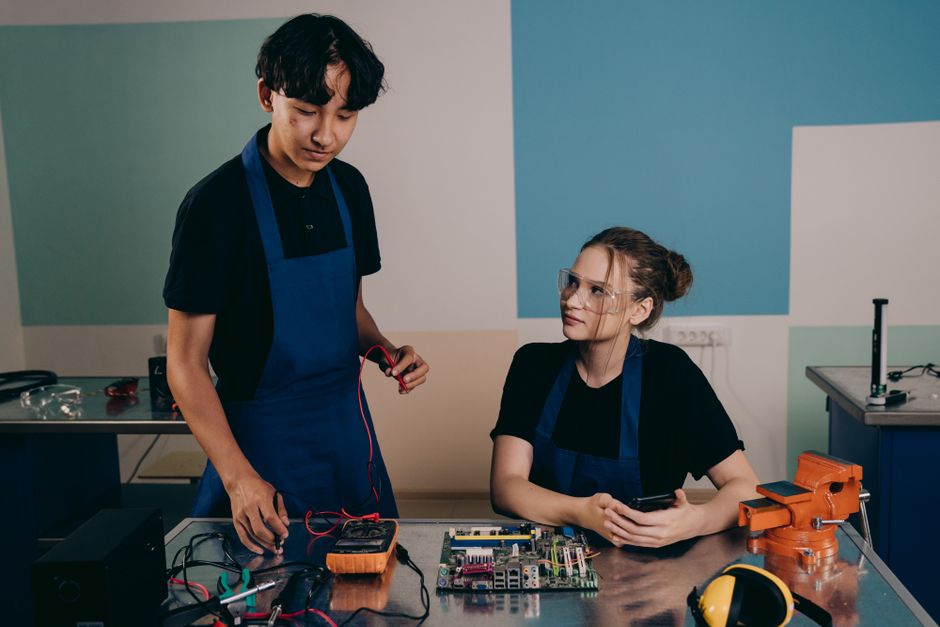 Two technicians working together on electronics, emphasizing teamwork and innovation.